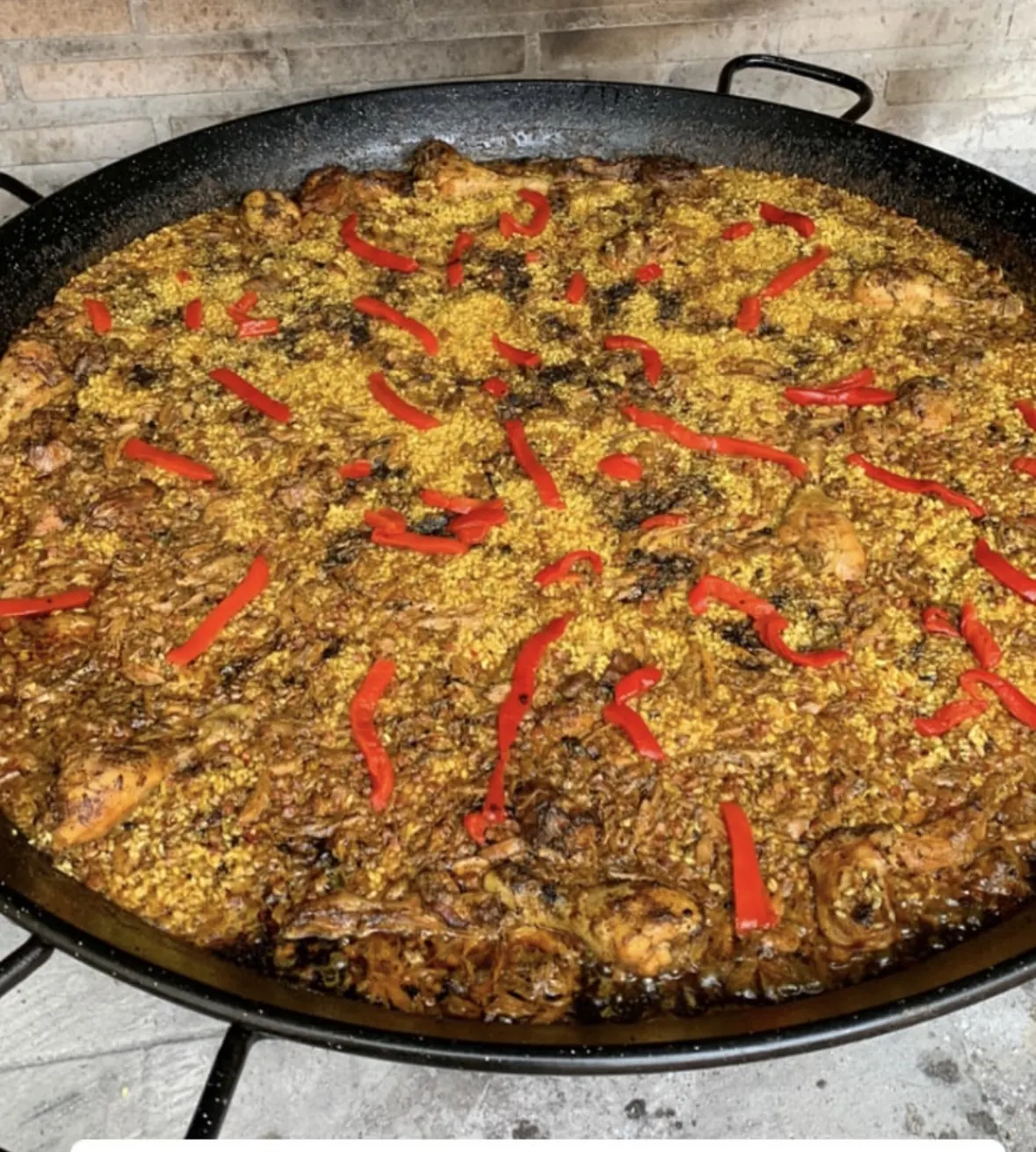 Paellera de arroz con pollo y tiras de pimiento rojo