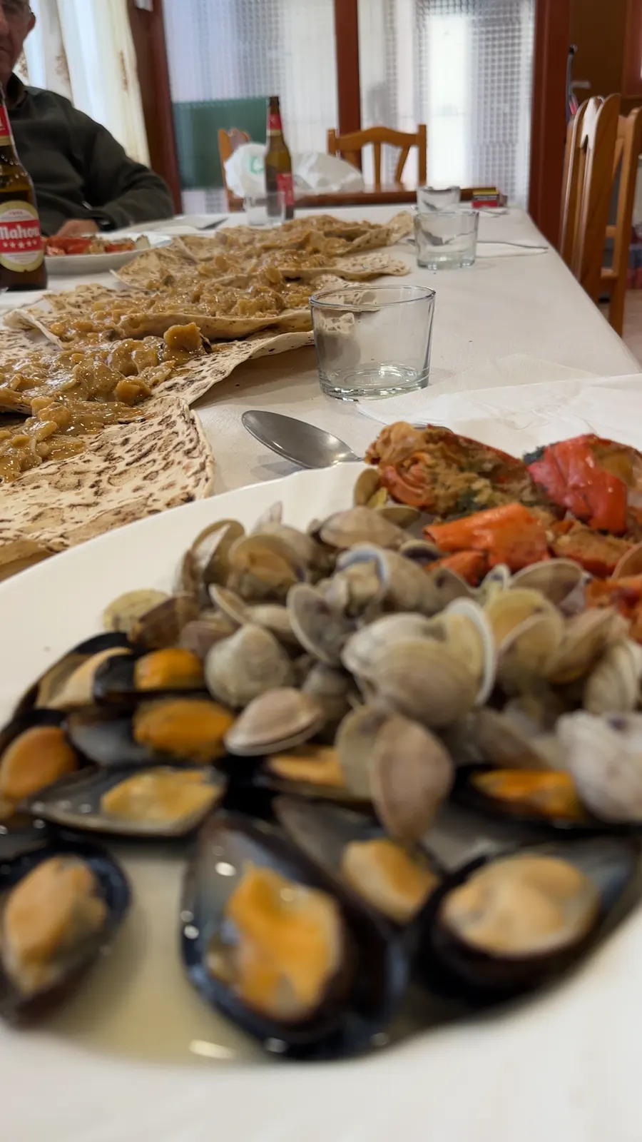 Mejillones y almejas para picar, con el gazpacho de marisco detrás en la mesa