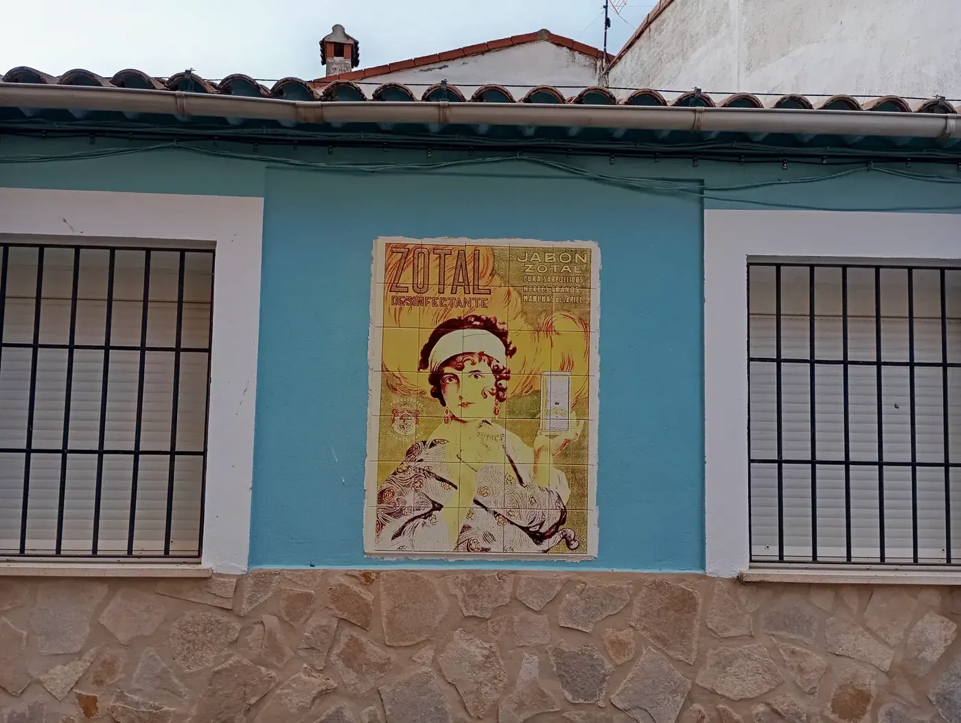 Fachada de Olmeda de la Cuesta con un anuncio antiguo del jabón Zotal en azulejo
